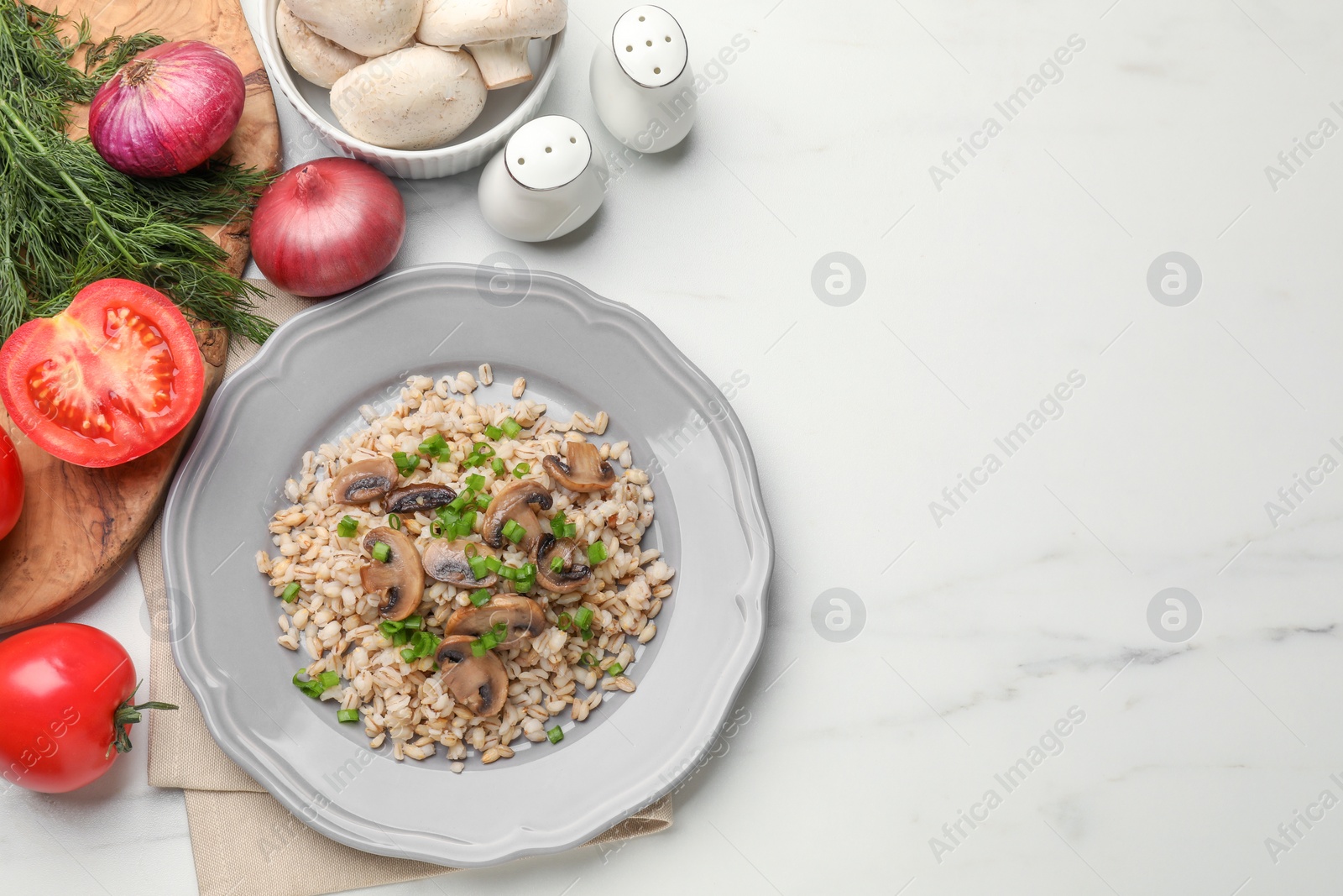 Photo of Delicious pearl barley with onion and mushrooms served on white marble table, flat lay. Space for text