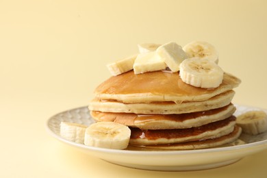 Photo of Delicious pancakes with bananas, honey and butter on beige background, closeup. Space for text