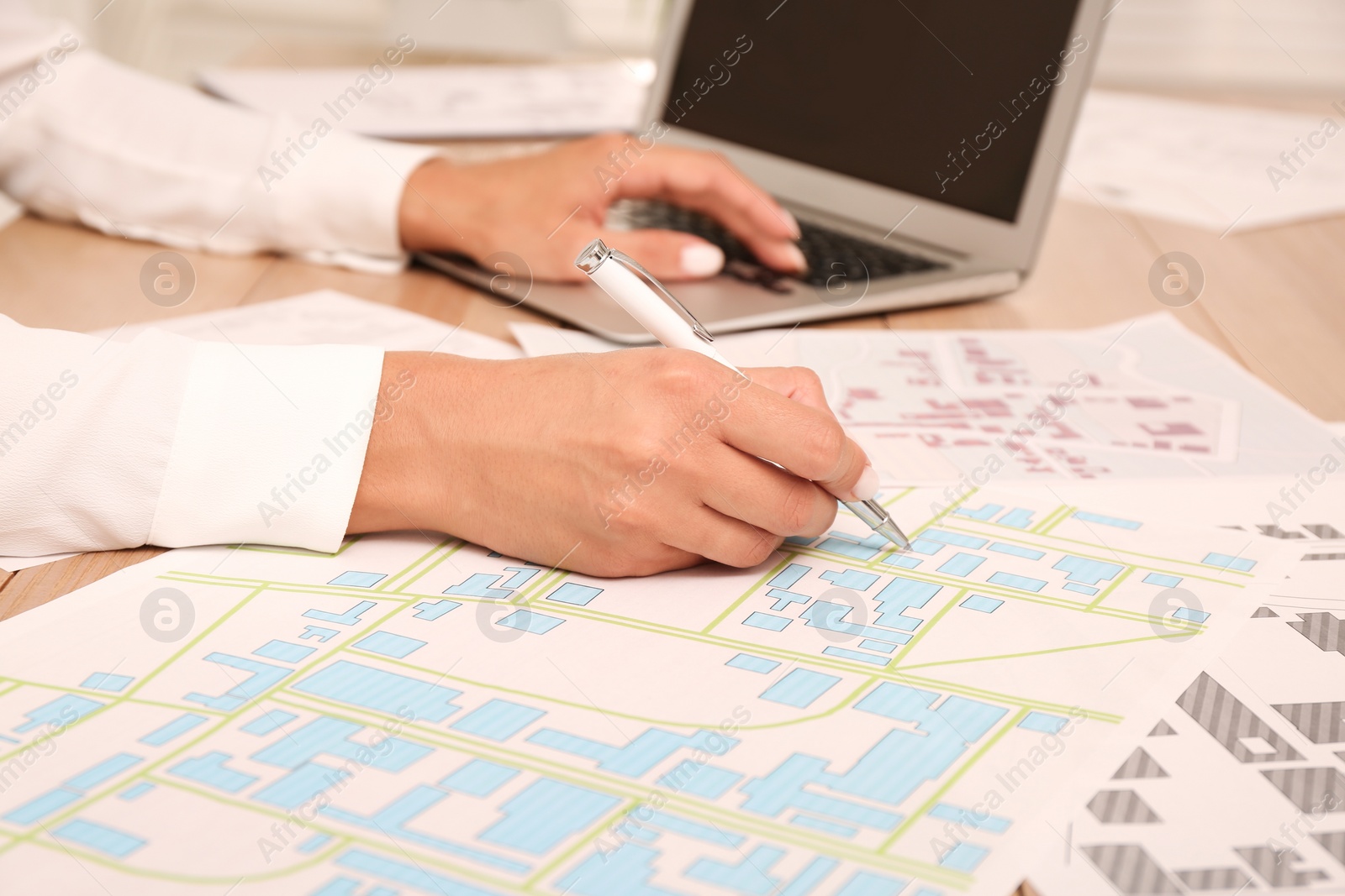 Photo of Professional cartographer working with cadastral map at wooden table, closeup