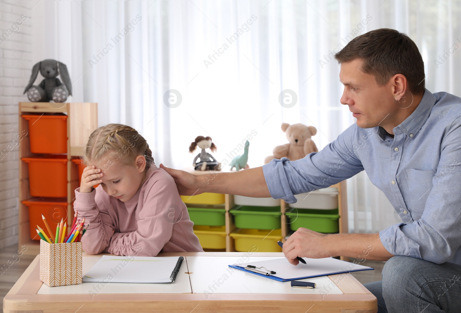 Photo of Child psychotherapist working with little girl in office