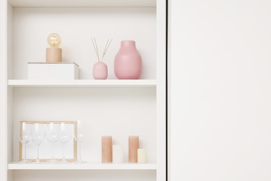 Photo of Shelves with different decor near white wall, space for text. Interior design