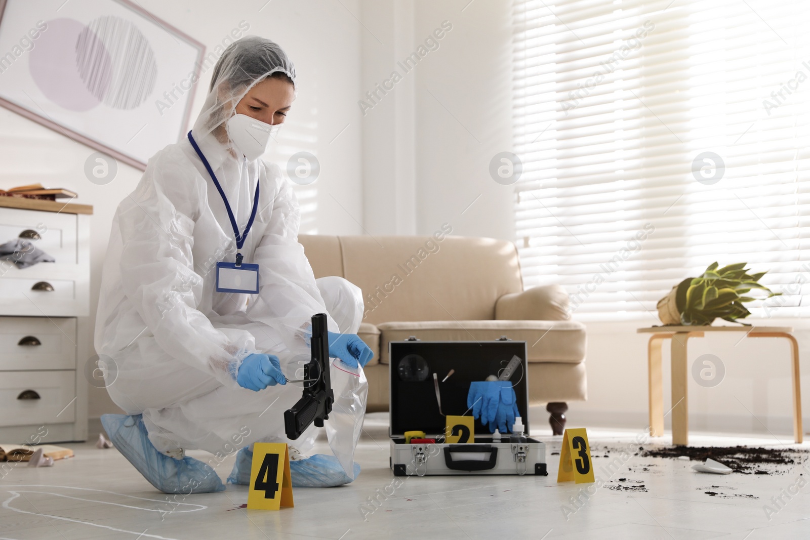 Photo of Investigator in protective suit working at crime scene indoors