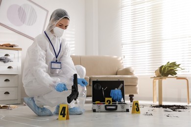 Investigator in protective suit working at crime scene indoors