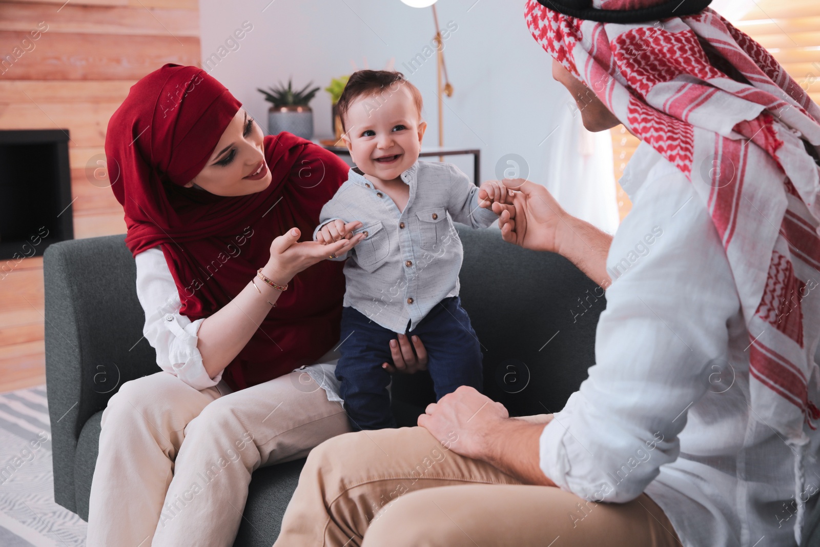 Photo of Happy Muslim family with little son in living room