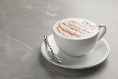 Photo of Cup of tasty caramel macchiato on table. Space for text