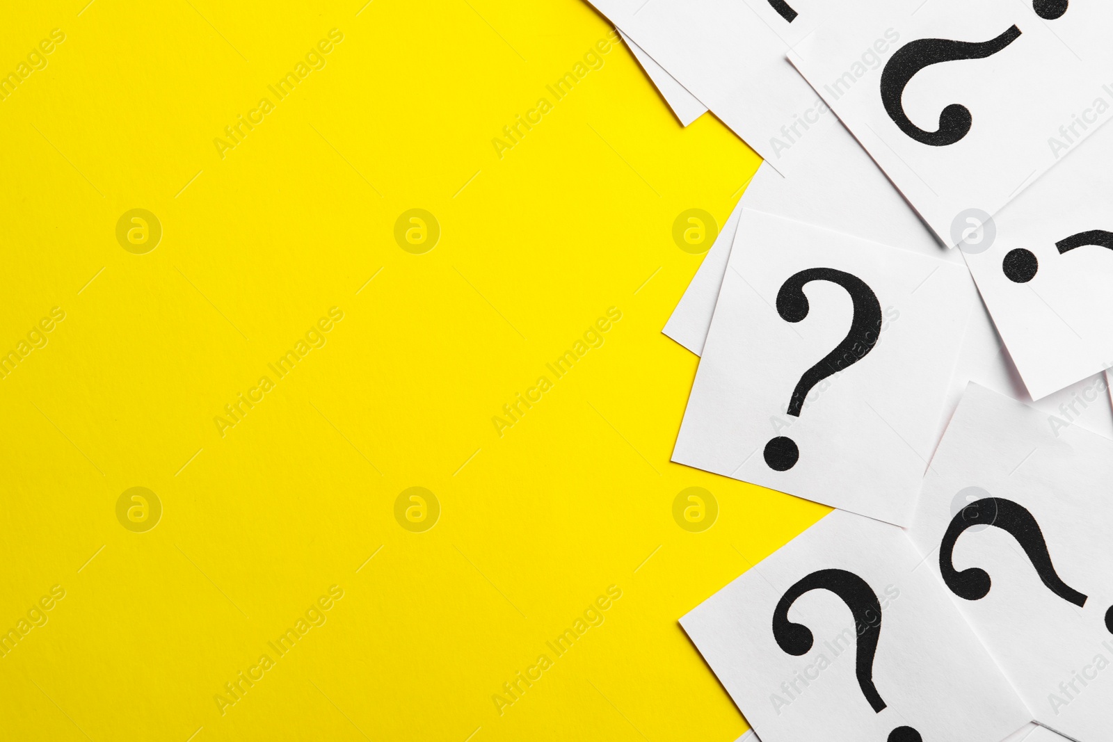 Photo of Paper notes with question marks on yellow background, flat lay. Space for text