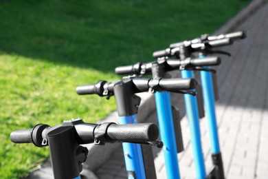 Many modern electric scooters outdoors, closeup. Rental service