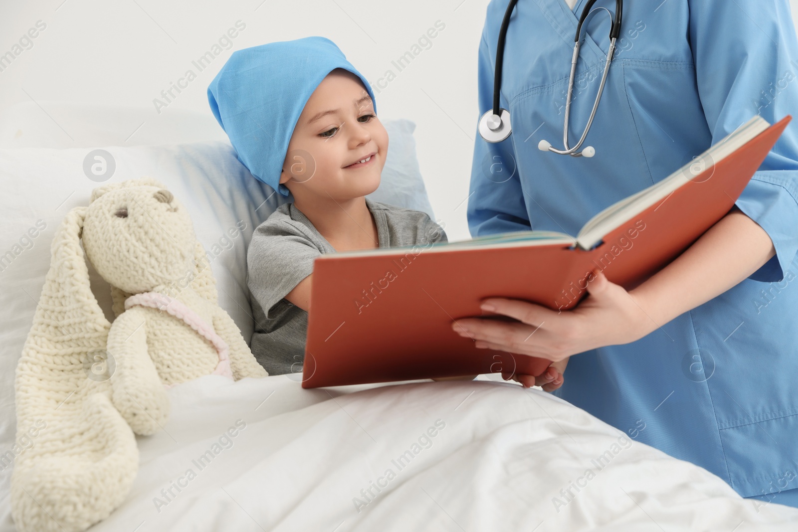 Photo of Childhood cancer. Doctor and patient reading book in hospital