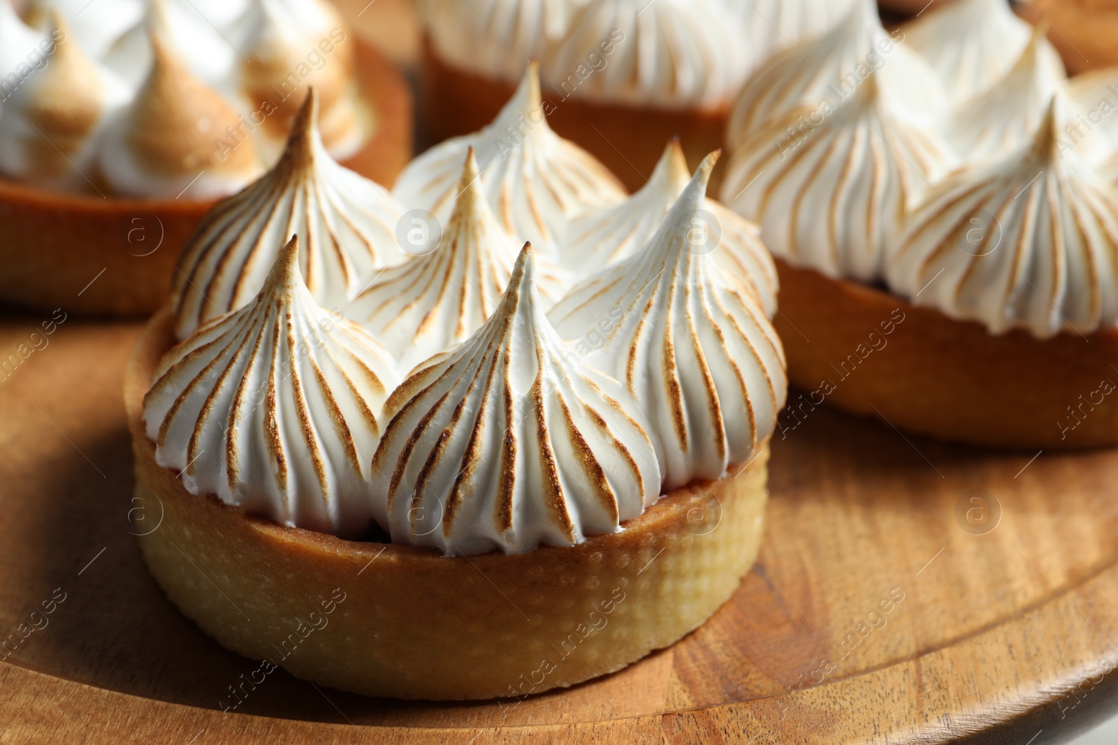 Photo of Tartlets with meringue on wooden table, closeup. Tasty dessert