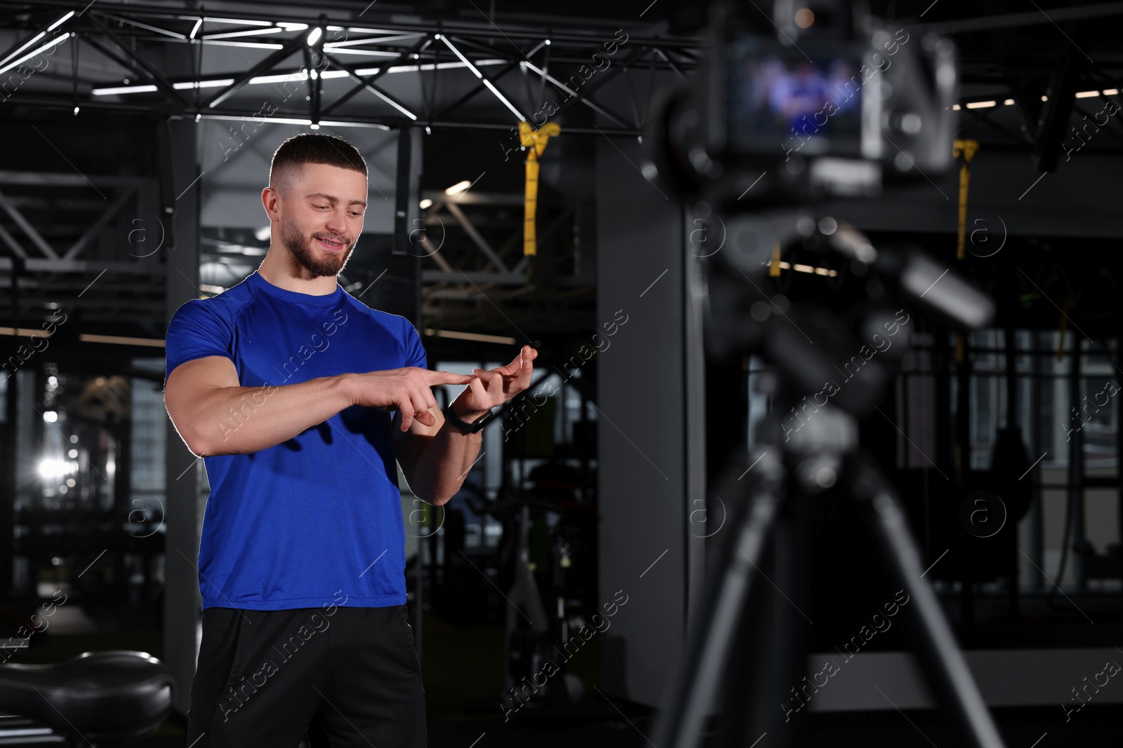 Photo of Man recording online training on camera at gym. Fitness coach