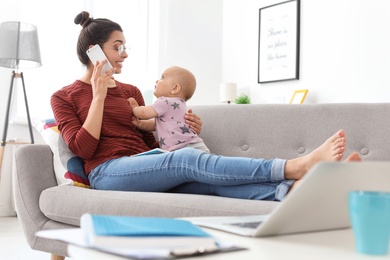 Photo of Young mother with her cute baby girl working at home