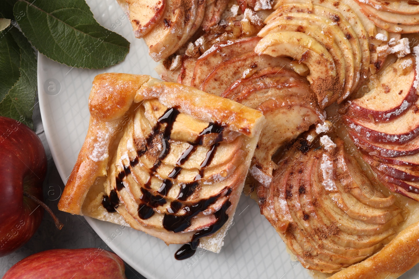 Photo of Tasty apple pie with chocolate topping, fresh fruits and green leaves on table, flat lay