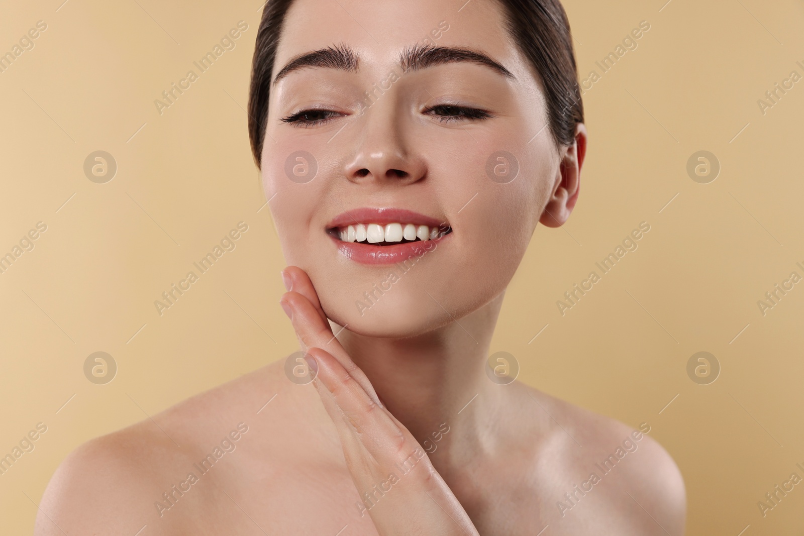 Photo of Young woman massaging her face on beige background