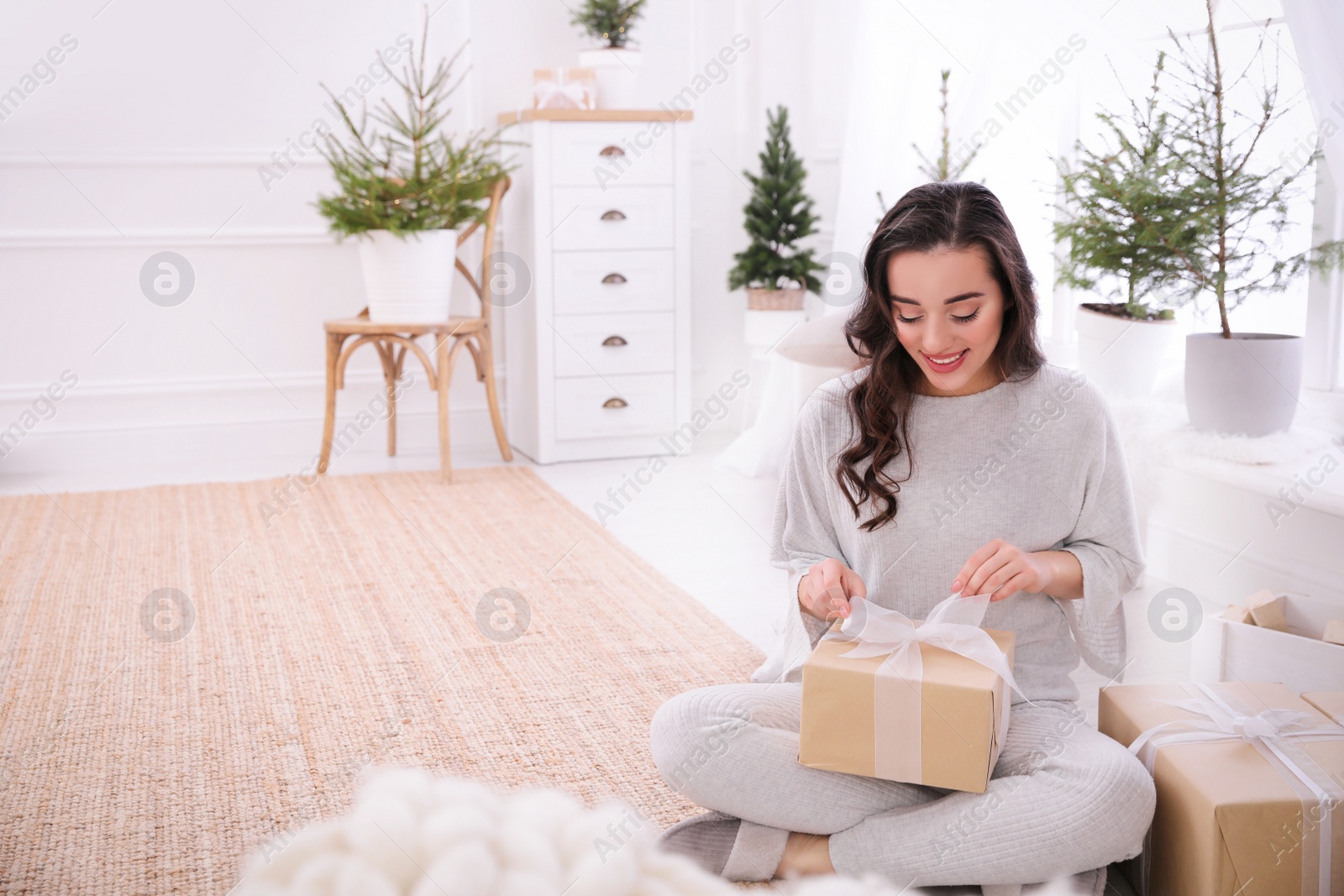 Photo of Woman with gift box on floor at home. Space for text