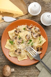 Photo of Delicious ravioli with mushrooms and cheese served on wooden table, flat lay