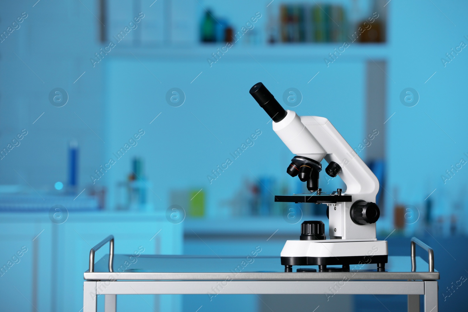 Photo of Modern medical microscope on metal table in laboratory, space for text