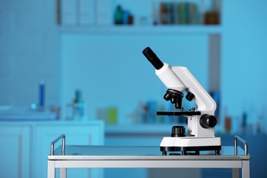 Photo of Modern medical microscope on metal table in laboratory, space for text