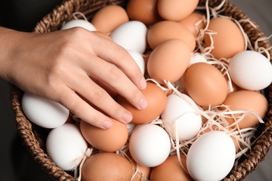 Photo of Woman with basket full of raw chicken eggs, closeup