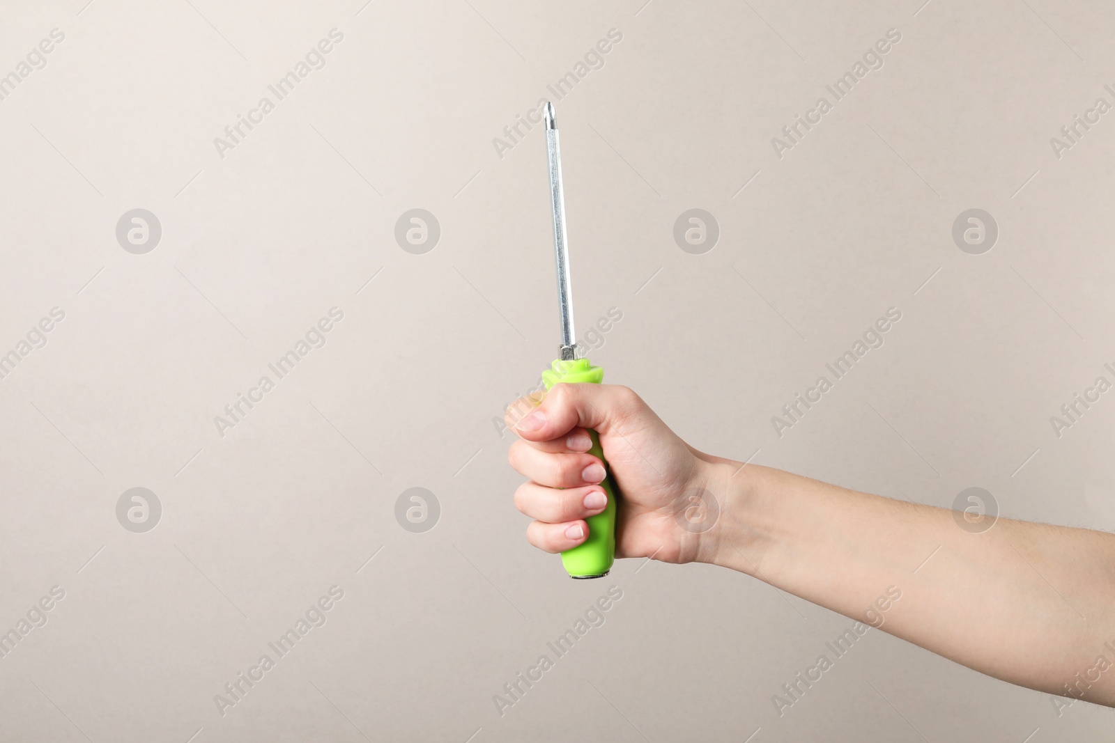 Photo of Woman holding screwdriver on grey background, closeup