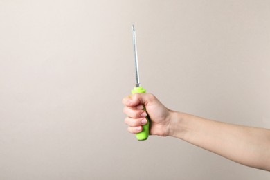 Photo of Woman holding screwdriver on grey background, closeup