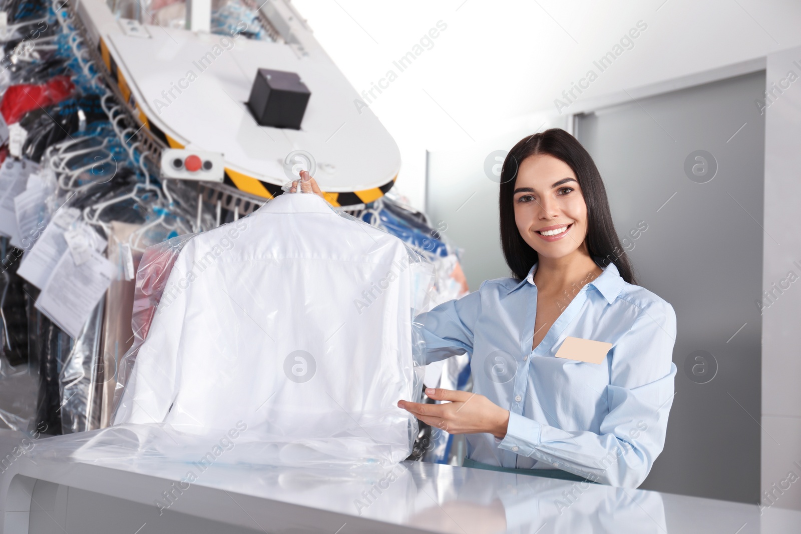 Photo of Female worker with shirt at modern dry-cleaner's