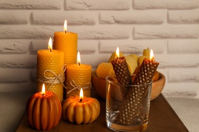 Photo of Beautiful burning beeswax candles on wooden table