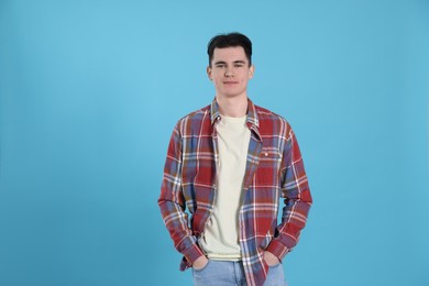 Portrait of handsome young man on light blue background, space for text