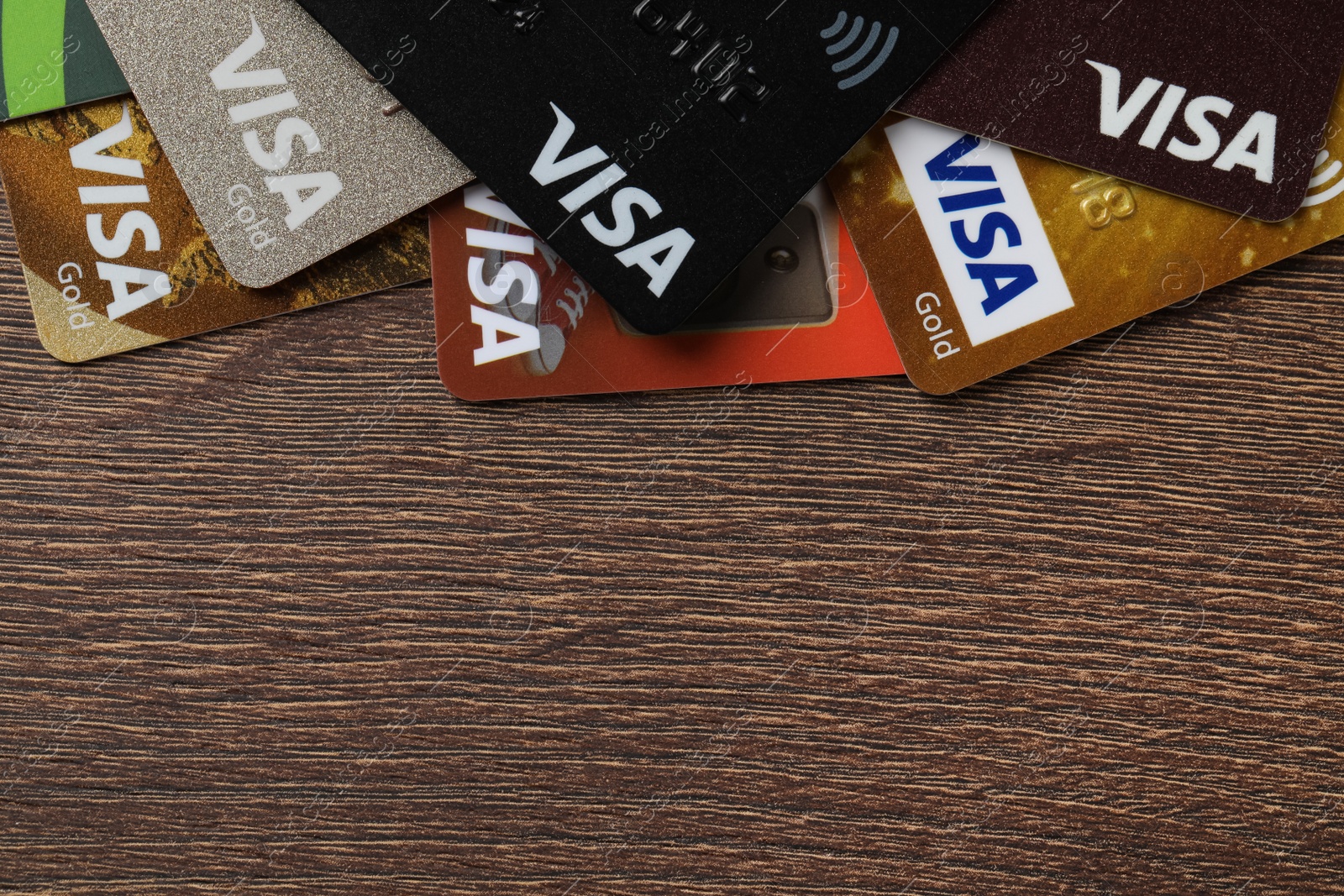 Photo of MYKOLAIV, UKRAINE - FEBRUARY 22, 2022: Visa credit cards on wooden table, flat lay. Space for text