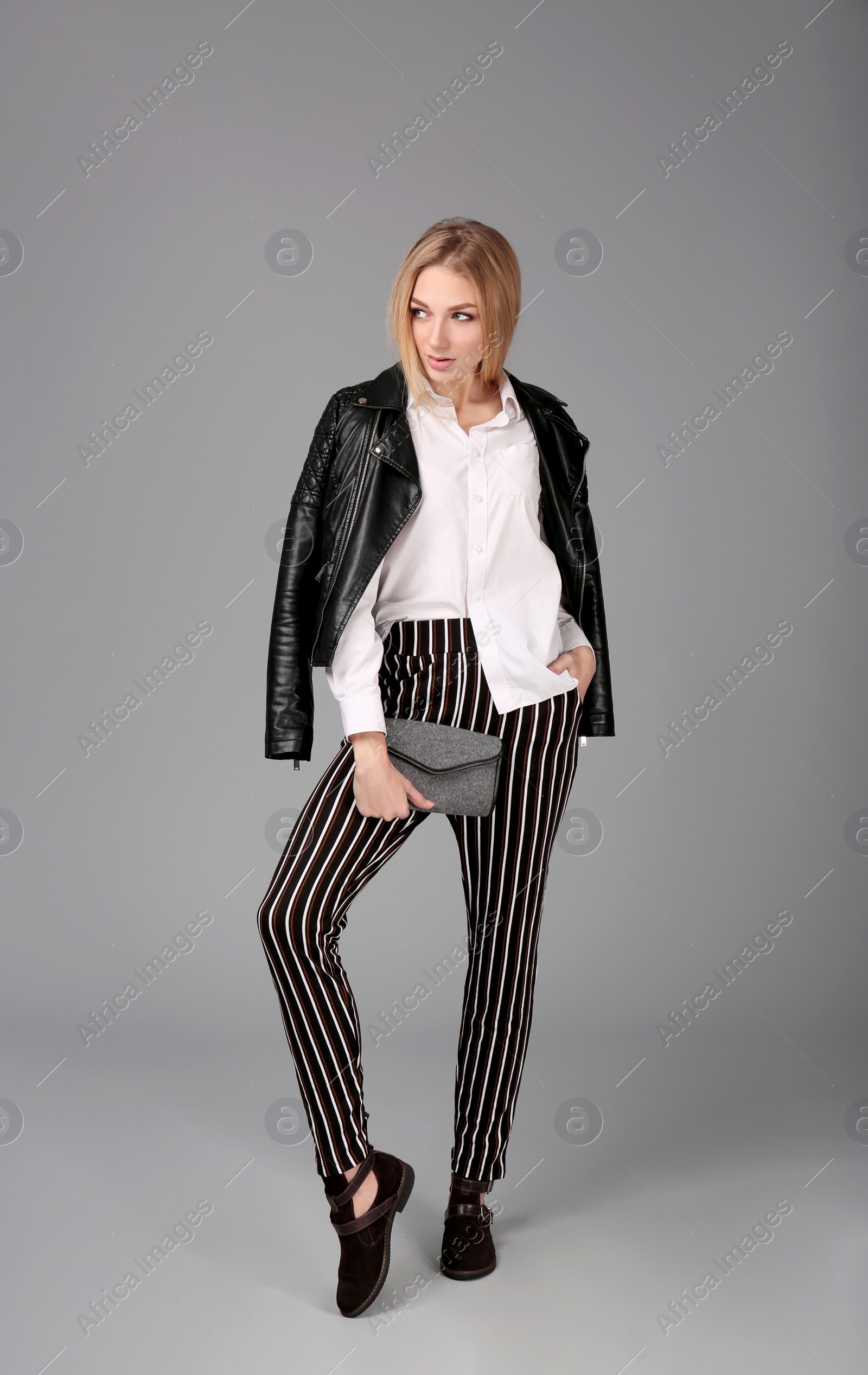 Photo of Young stylish woman in trendy shoes with bag on grey background