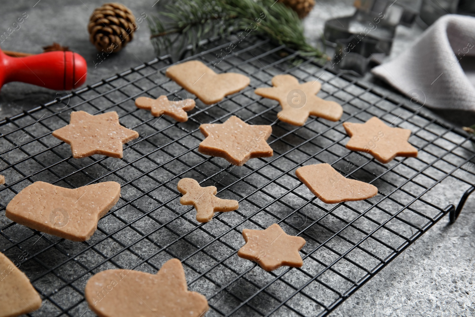 Photo of Homemade Christmas cookies. Baking rack with raw gingerbread biscuits on grey table, closeup