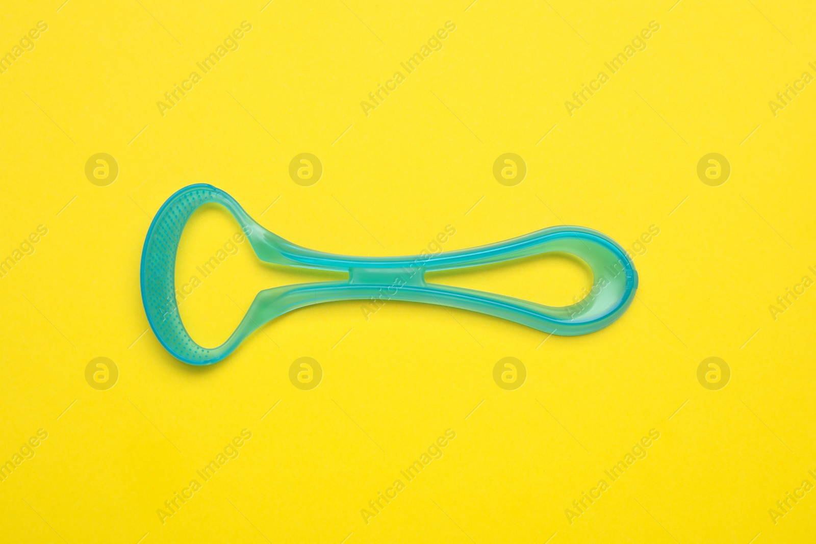 Photo of Tongue cleaner on yellow background, top view