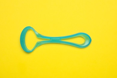 Photo of Tongue cleaner on yellow background, top view