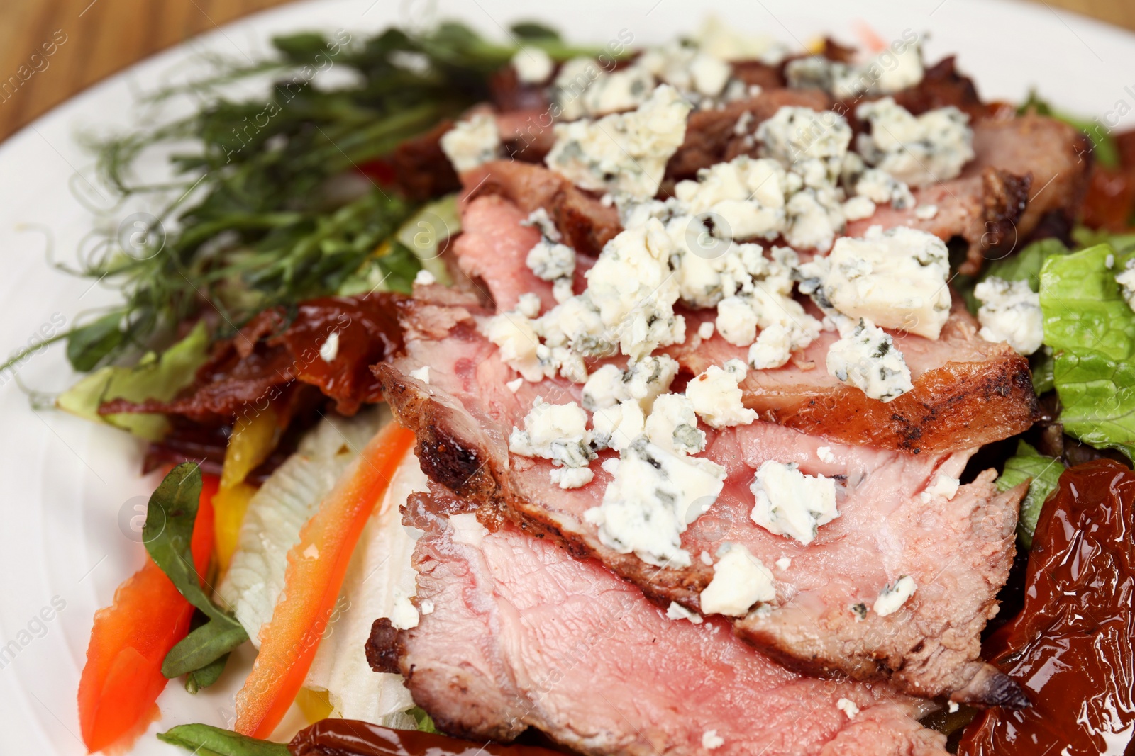 Photo of Delicious salad with roasted meat and vegetables on plate, closeup