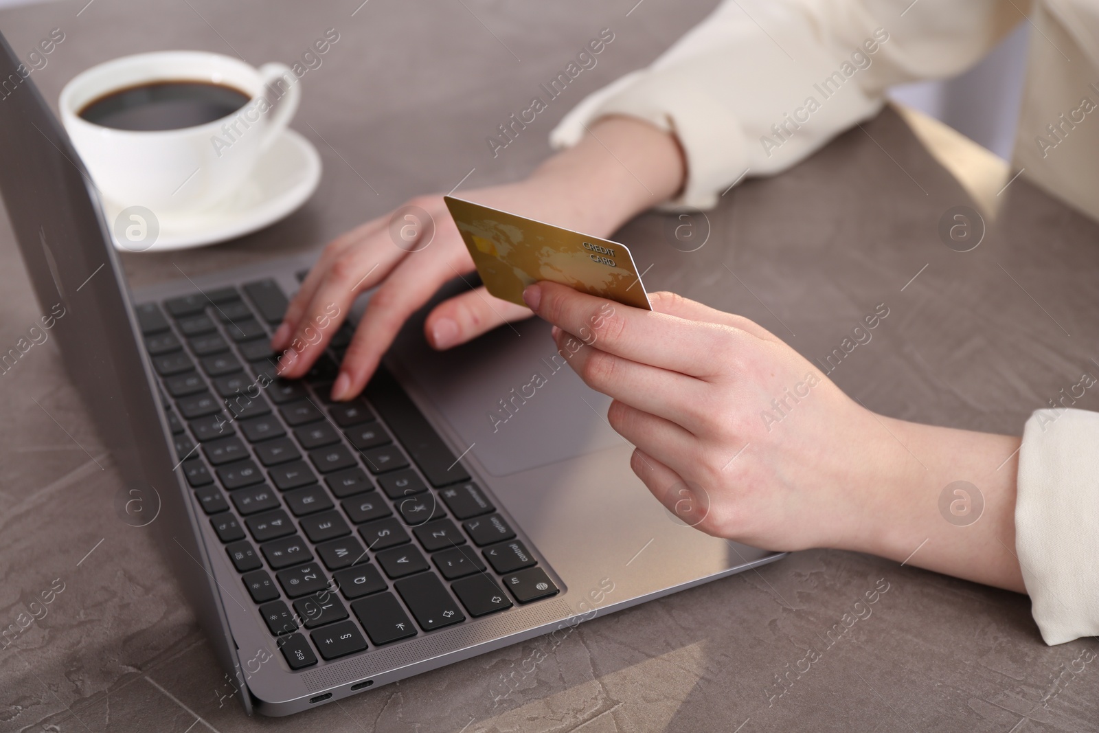 Photo of Online payment. Woman with laptop and credit card at grey table, closeup