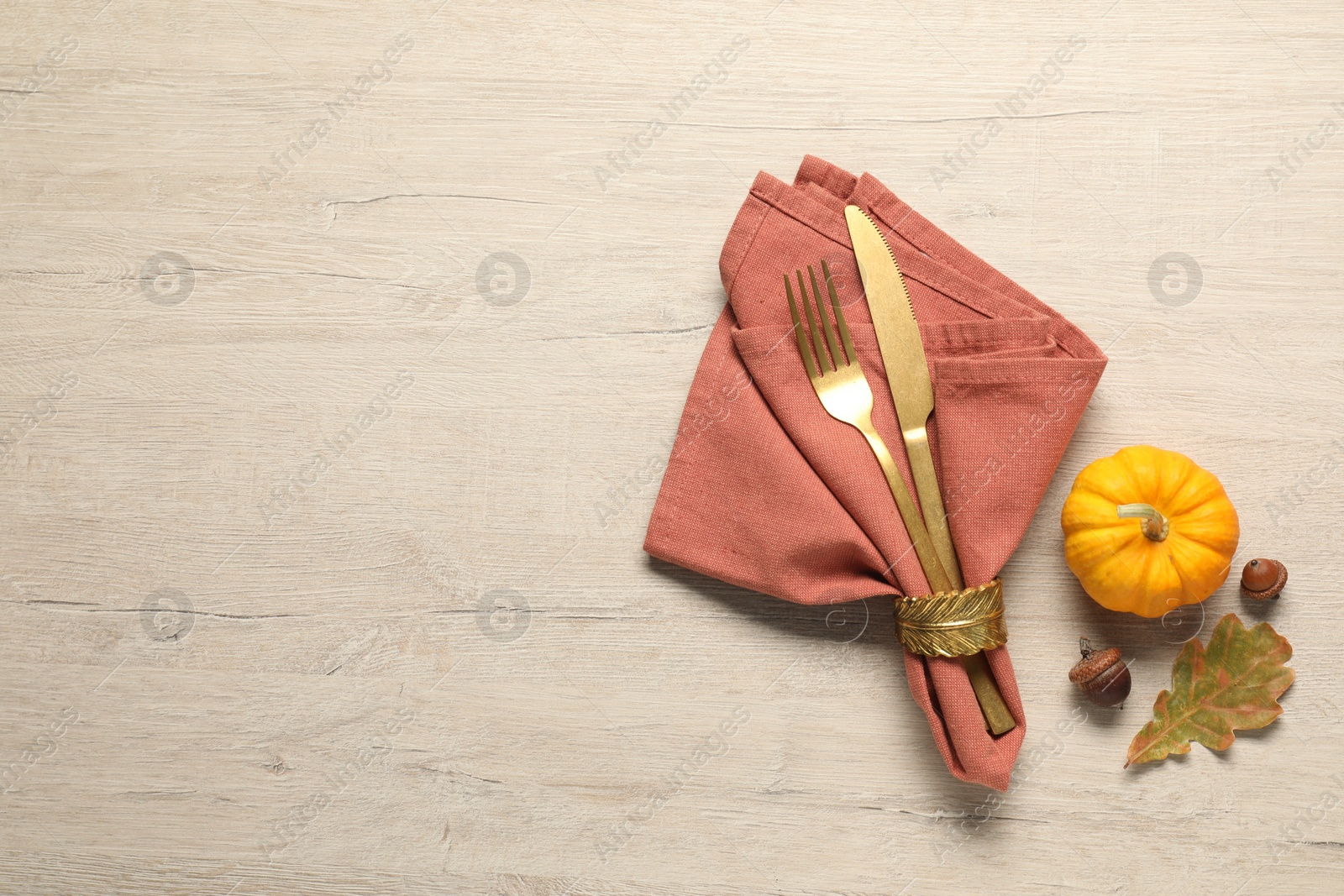 Photo of Cutlery, napkin and pumpkin on wooden background, flat lay with space for text. Table setting