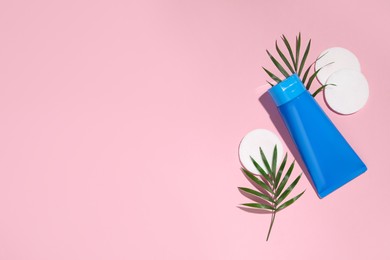 Photo of Tube of face cleansing product, leaves and cotton pads on pink background, flat lay. Space for text