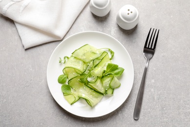 Photo of Plate with delicious cucumber salad served on grey table, top view