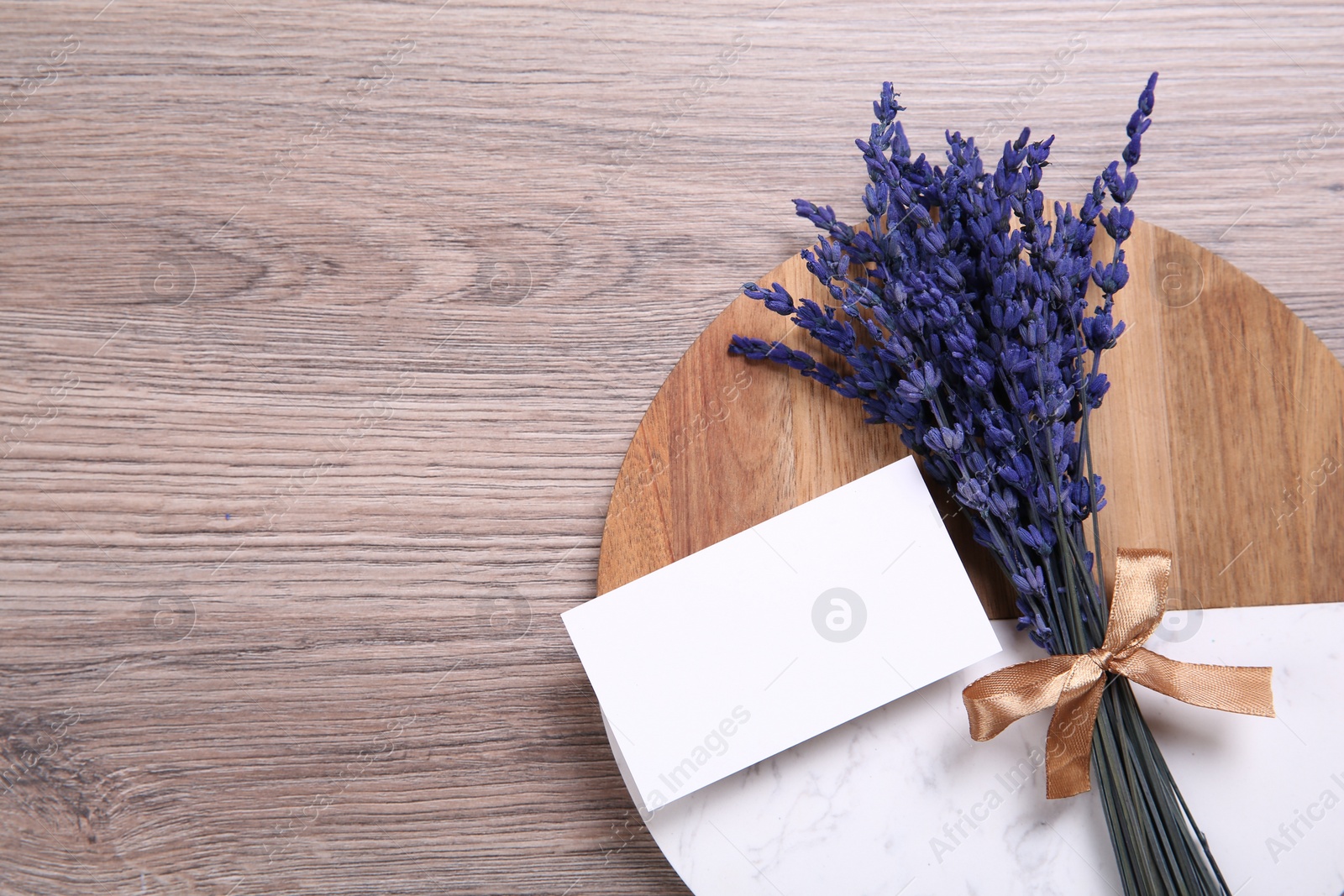 Photo of Bouquet of beautiful preserved lavender flowers, blank card and board on wooden table, top view. Space for text