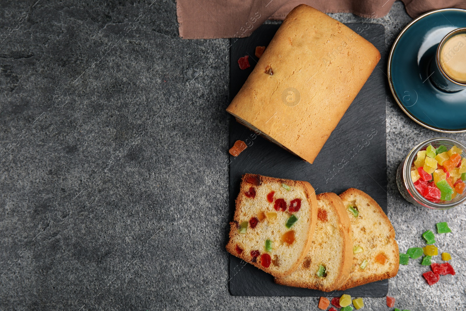 Photo of Delicious cake with candied fruits and coffee on grey table, flat lay. Space for text