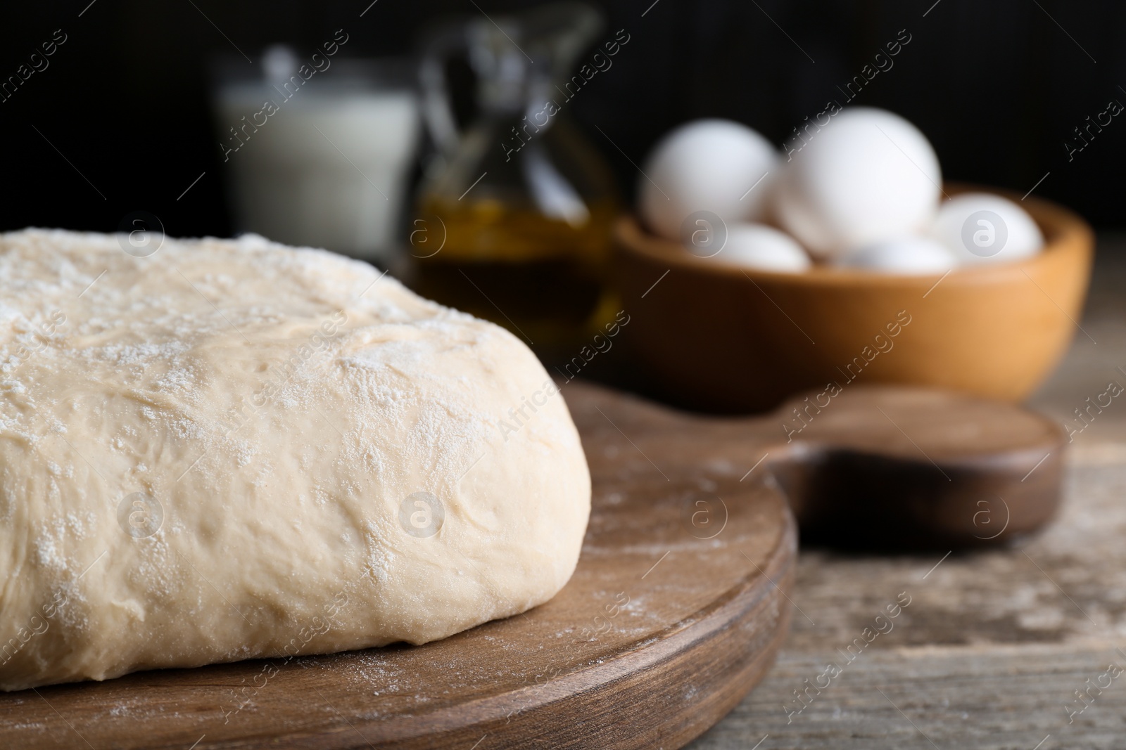 Photo of Fresh yeast dough with flour on wooden table, closeup. Space for text
