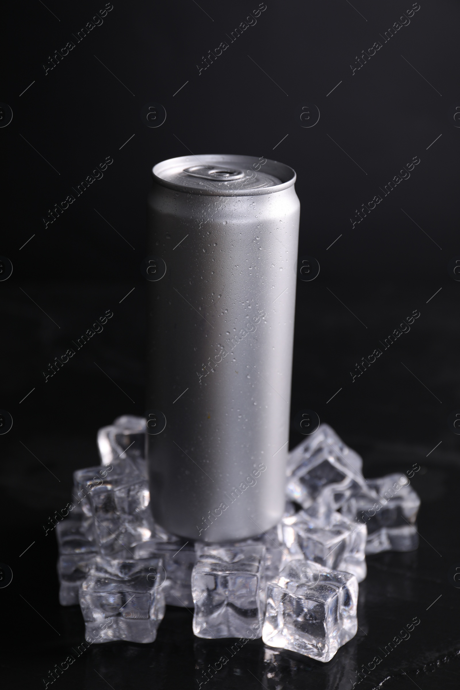 Photo of Aluminium can of energy drink and ice cubes on black table