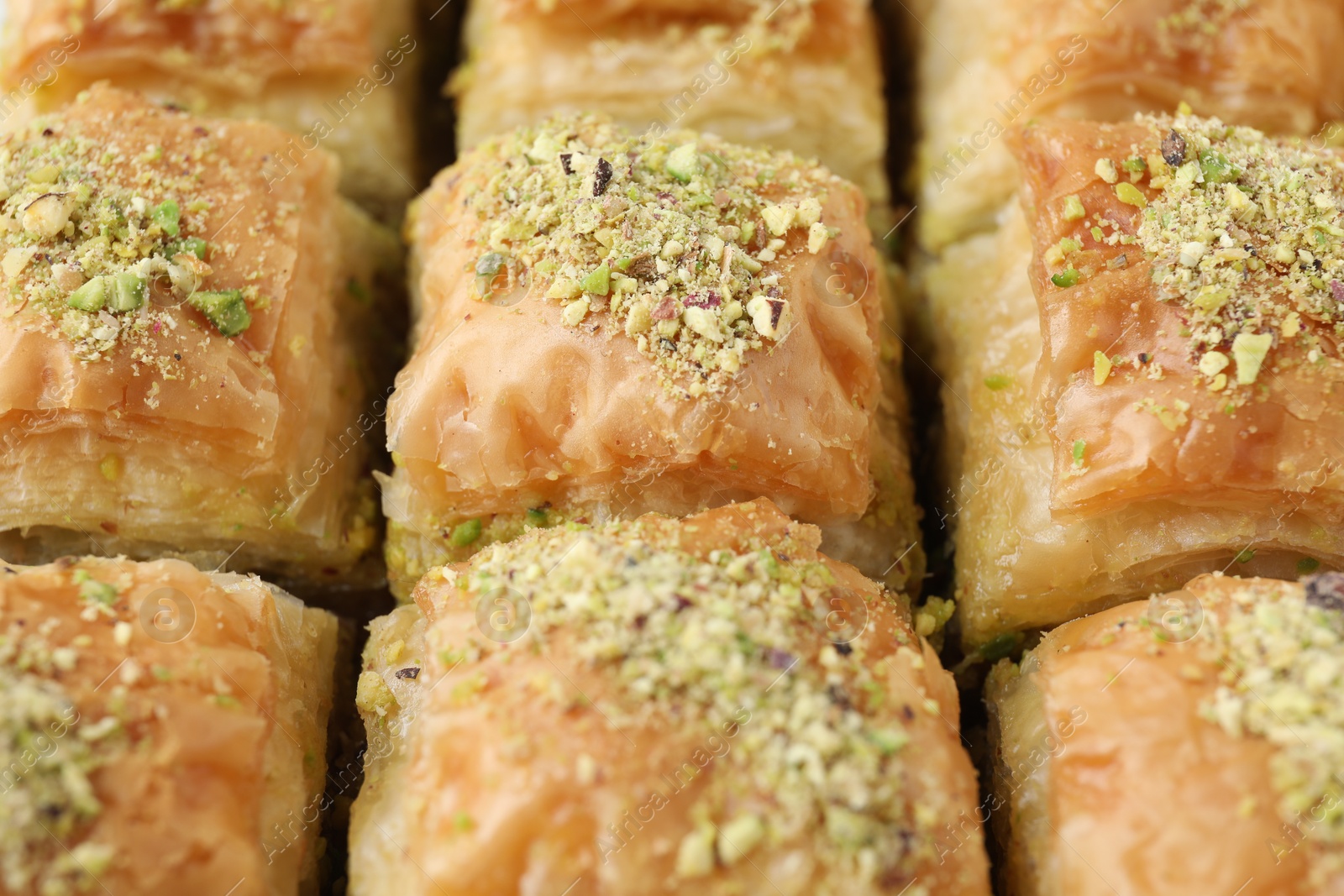 Photo of Delicious fresh baklava with chopped nuts as background, closeup. Eastern sweets