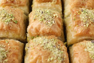 Photo of Delicious fresh baklava with chopped nuts as background, closeup. Eastern sweets