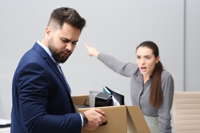 Boss dismissing young man from work in office