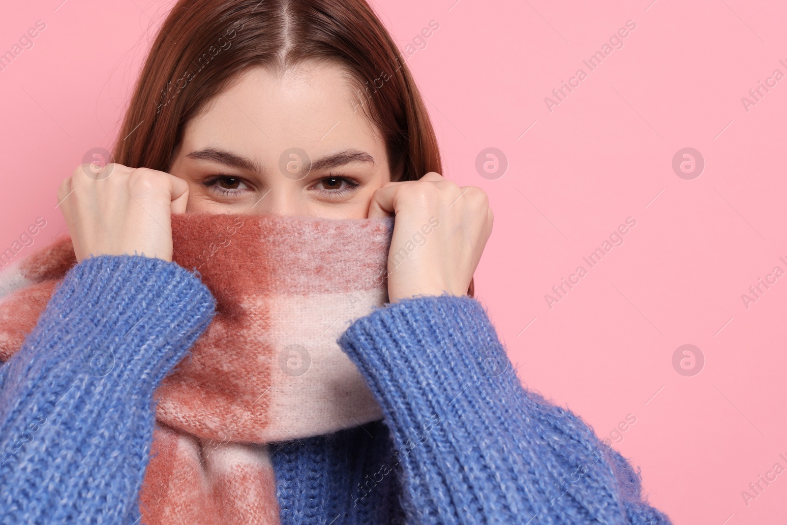 Photo of Beautiful woman in warm scarf on pink background, space for text