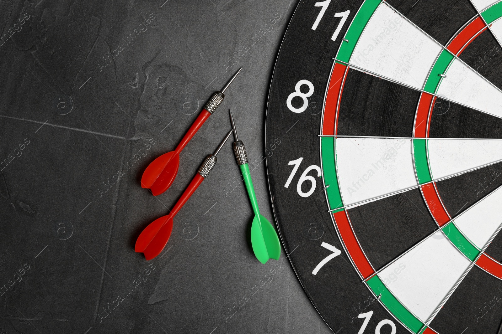 Photo of Dart board with color arrows on grey stone background, top view