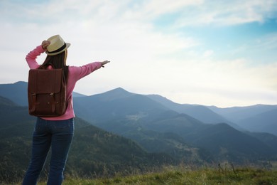 Woman enjoying mountain landscape, back view. Space for text