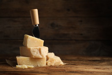 Photo of Delicious parmesan cheese and knife on wooden table. Space for text