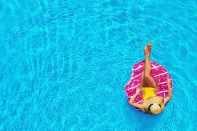 Image of Young woman with inflatable ring in swimming pool, top view. Space for text