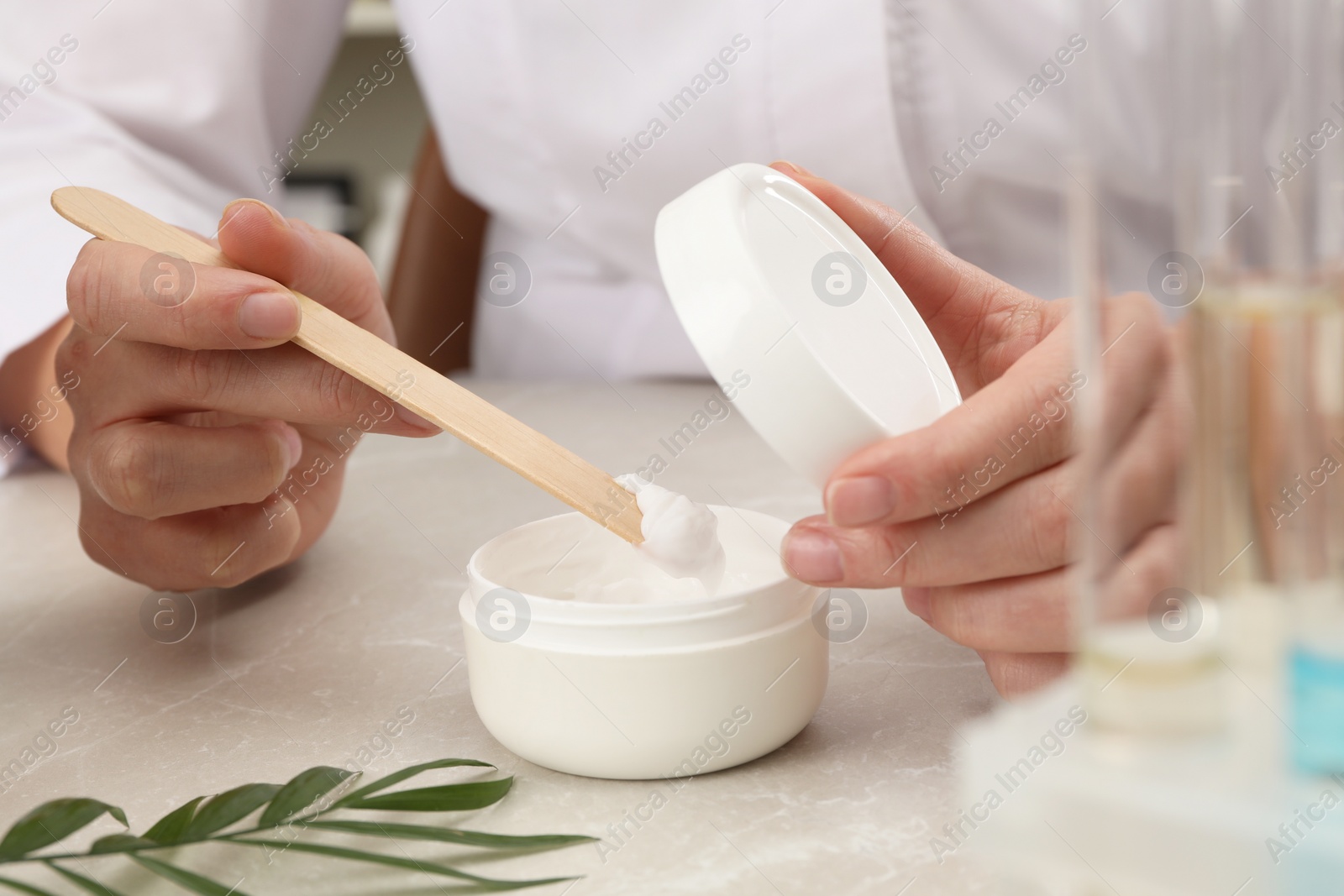 Photo of Dermatologist developing cosmetic product at light marble table, closeup